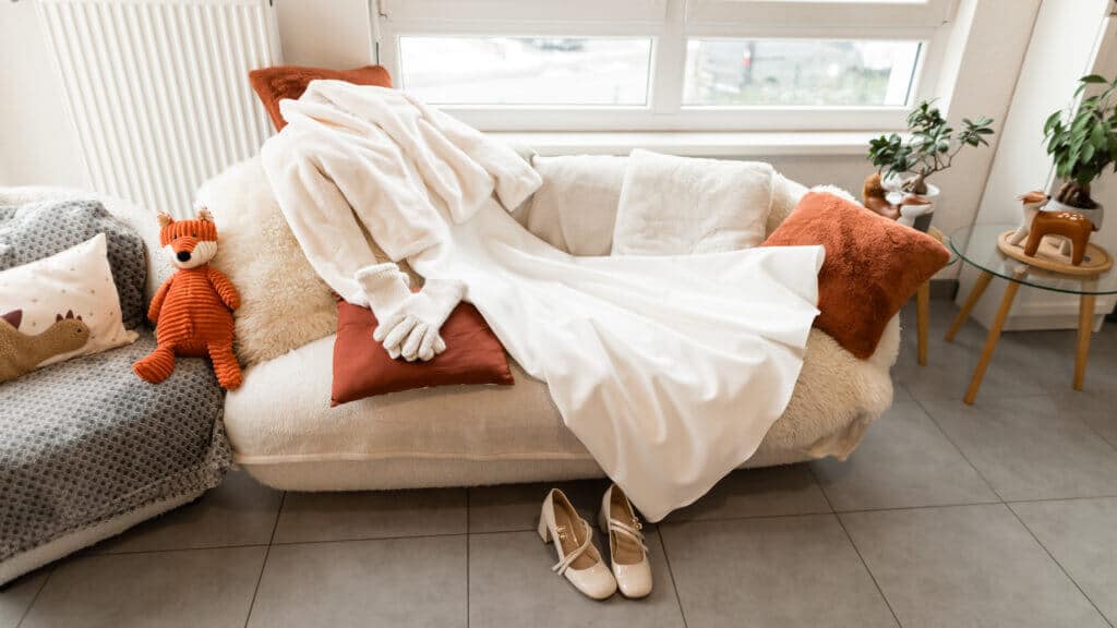 Préparatif de mariage : La robe d'hiver de la mariée est étendu que la canapé avec les accessoire. Il y a les chaussures sont devant le canapé. Il y a aussi un renard en peluche sur le coté